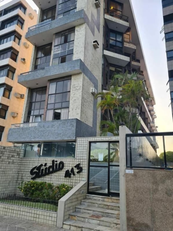 A modern building with a tiled facade, a visible entrance with steps, and a sign that reads "Studio 13".