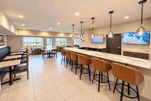 Un área de cocina moderna con encimera de mármol, taburetes de bar e iluminación colgante.