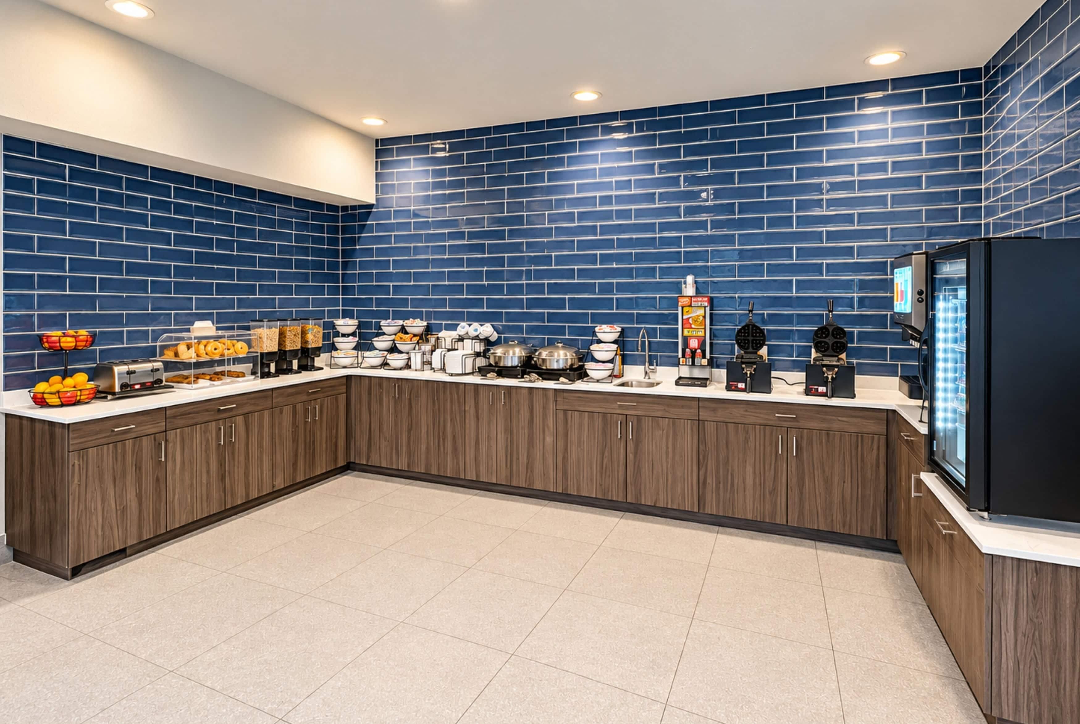 A modern kitchen with a blue-tiled backsplash, a built-in refrigerator, and a variety of breakfast items on the counter.