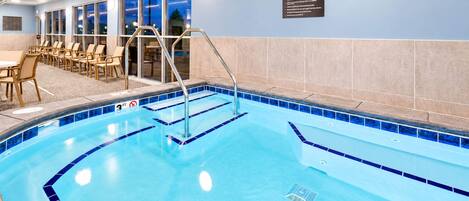 Une piscine intérieure à l’eau d’un bleu cristallin, dont la profondeur est indiquée à 3 pieds, et sur laquelle est affiché un panneau indiquant les règles du centre de bien-être.