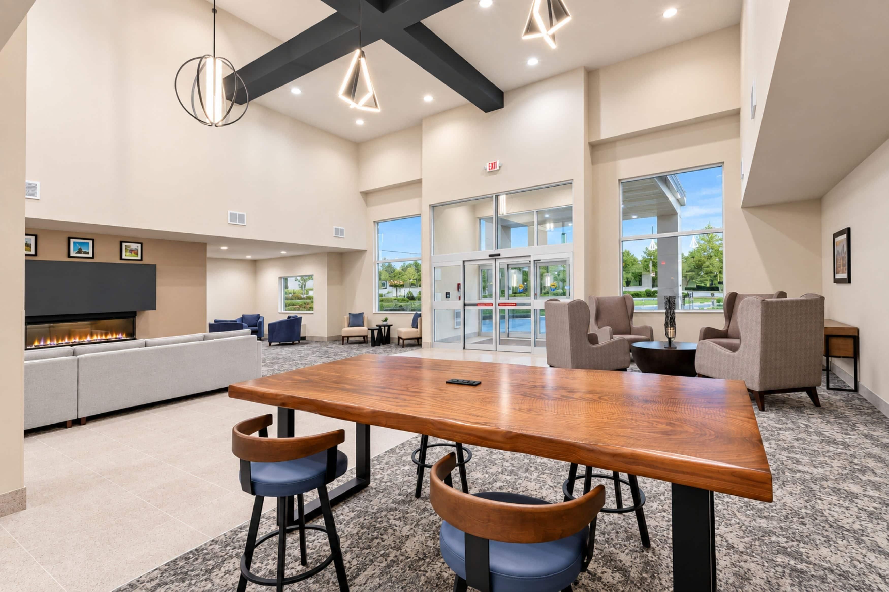 A modern lounge area with a wooden table, bar stools, and seating.