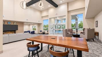 Un área de lounge moderna con una mesa de madera, taburetes de bar y asientos.
