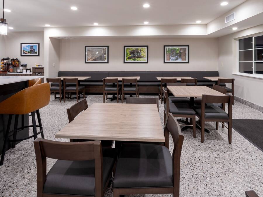 A restaurant with multiple tables and booths, a bar area, and framed pictures on the wall.