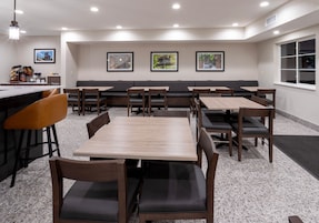 A restaurant with multiple tables and booths, a bar area, and framed pictures on the wall.