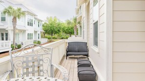 A balcony with wicker furniture, a white railing, and a view of neighboring houses. - Emerald Gem by Avantstay Pool Access, 3mins to Beach! (Santa Rosa Beach)