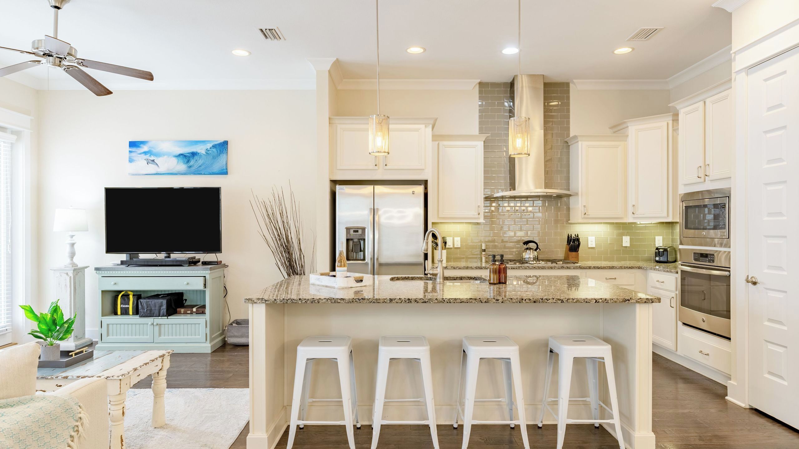 A modern kitchen with a central island, stainless steel appliances, and a flat-screen TV.