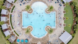 An aerial view of a resort with a central swimming pool, surrounded by lounge areas and palm trees. - Emerald Gem by Avantstay Pool Access, 3mins to Beach! (Santa Rosa Beach)