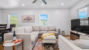 A modern living room with a sectional sofa, a television, a dining area with chairs, and a patterned rug. - Little Pisgah Sunrise by Avantstay Mountain View (Fairview)