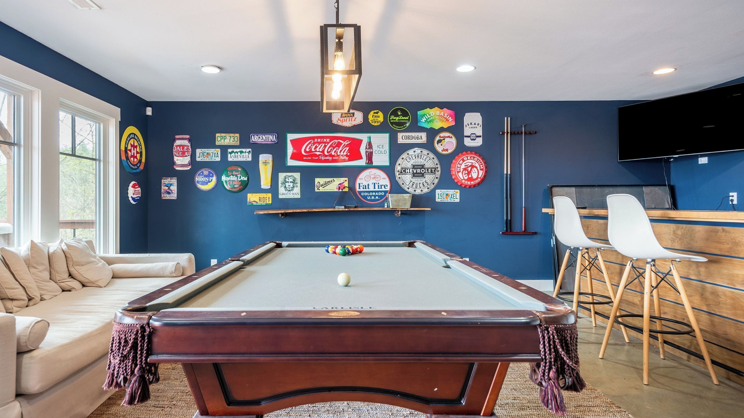 Ein Billardtisch in einem Raum mit blauer Wand, einer Couch und einer Bar.
