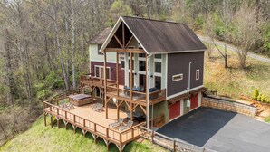 A two-story cabin with a deck, outdoor seating, and a garage. - Private Retreat w/ Hot Tub, Amazing Views, Game Room Silver Spoon by Avantstay (Leicester)