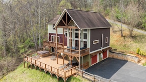 A two-story cabin with a deck, outdoor seating, and a garage. - Private Retreat w/ Hot Tub, Amazing Views, Game Room Silver Spoon by Avantstay (Leicester)