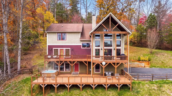 A two-story house with a deck, large windows, and a chimney.
