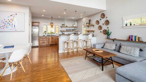 A modern kitchen with a central island, wooden cabinets, and a dining area with a white table and chairs. - Private Retreat w/ Hot Tub, Amazing Views, Game Room Silver Spoon by Avantstay (Leicester)