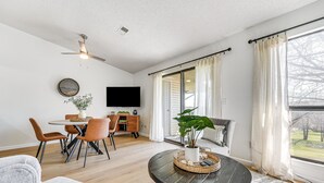 A spacious living room with a dining area, a large window with curtains, a ceiling fan, and a flat-screen TV. - 5 Mi to Strip! Pointe Royale Condo w/ Indoor Pool (Branson)