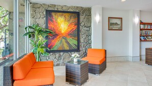 Un hall con mobiliario de mimbre, una pared de piedra y una estantería.