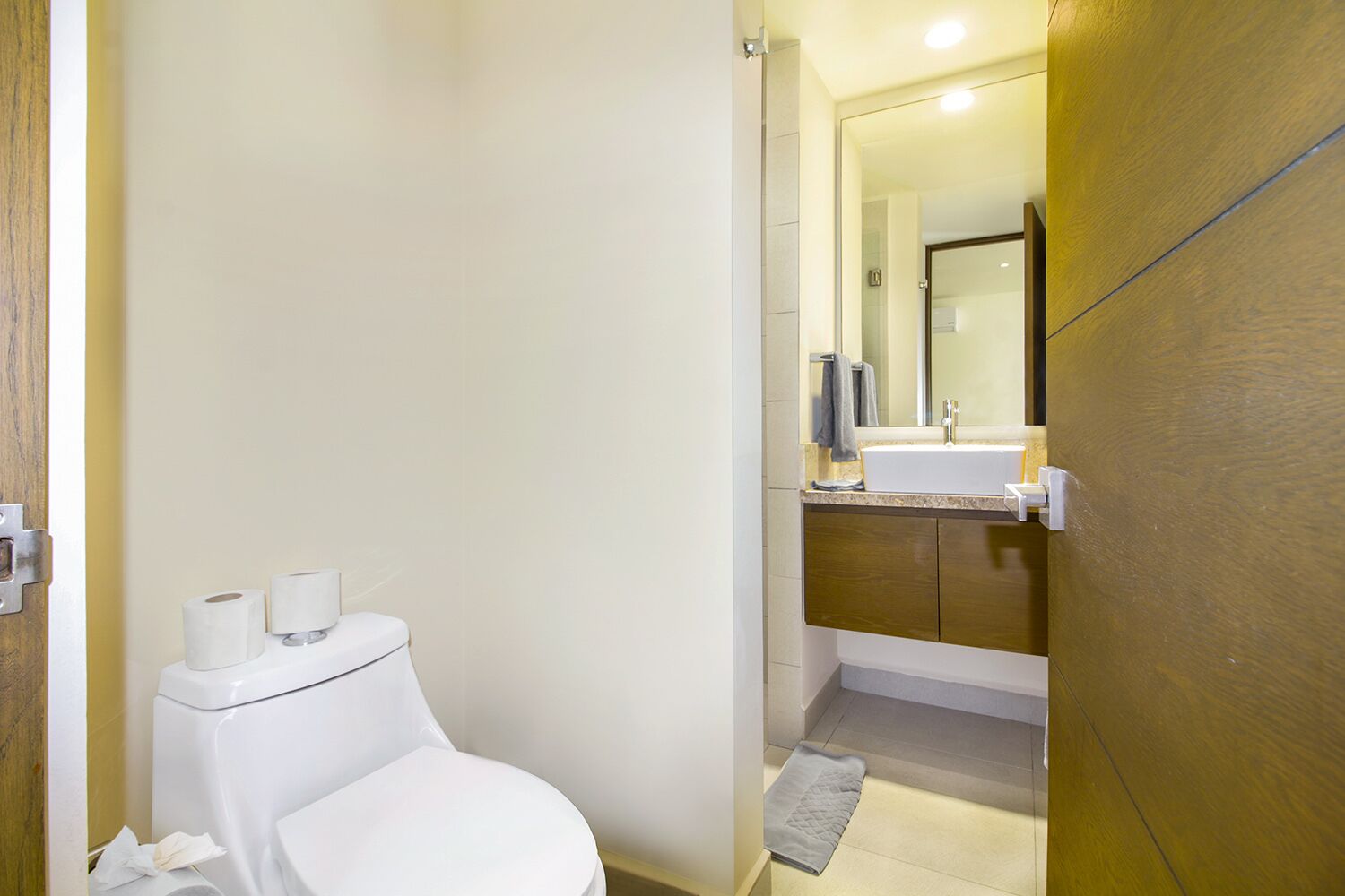 Un baño moderno con inodoro, lavabo y espejo.