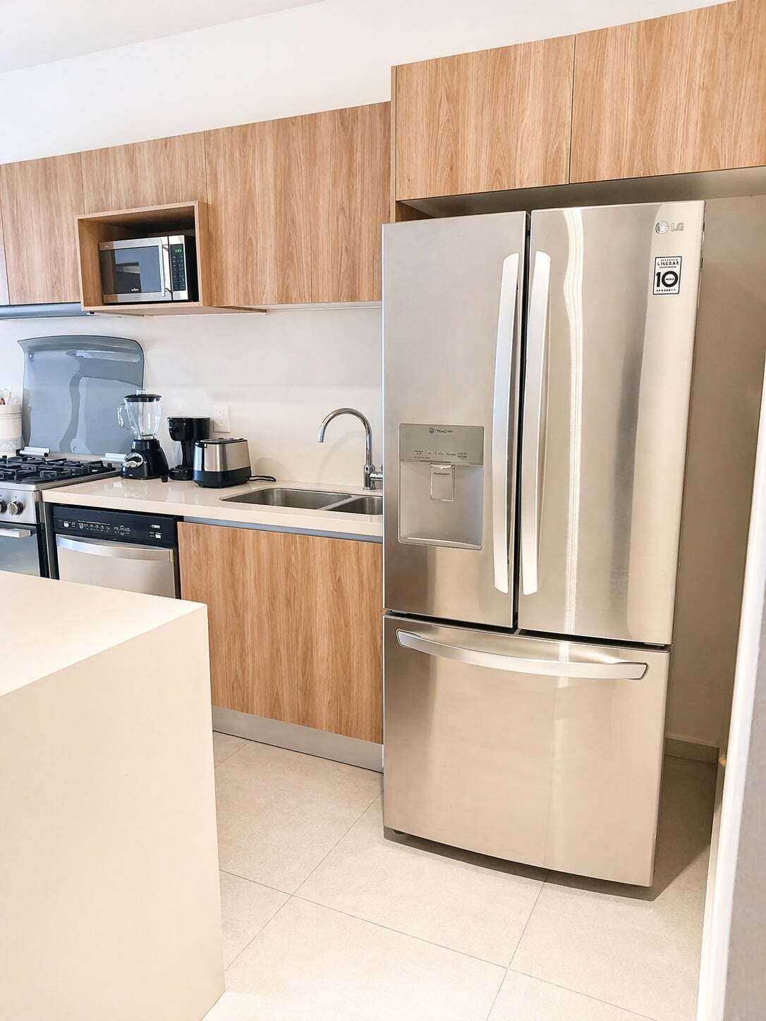 Una cocina moderna con electrodomésticos de acero inoxidable, armarios de madera y microondas integrado.