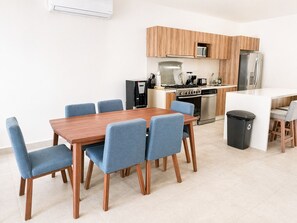 Una cocina moderna con armarios de madera, estufa a gas, horno, microondas y cafetera.
