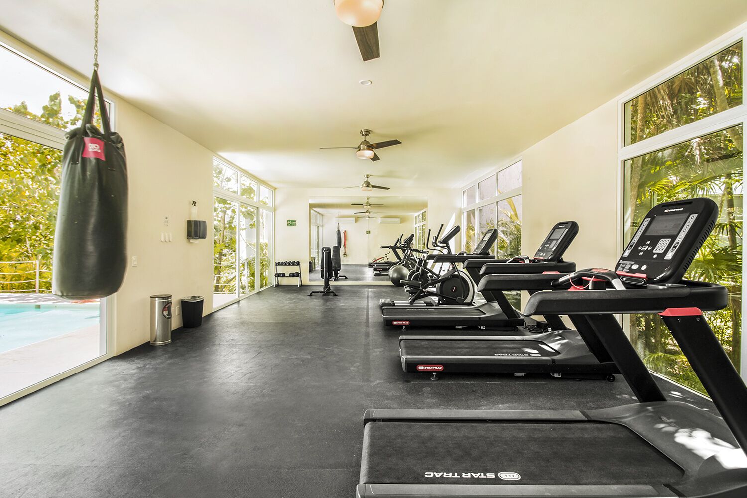 A gym with treadmills, weights, and a punching bag.