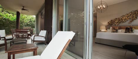 A modern living room with a sofa, a coffee table, and a chair. There is a sliding glass door leading to a balcony.