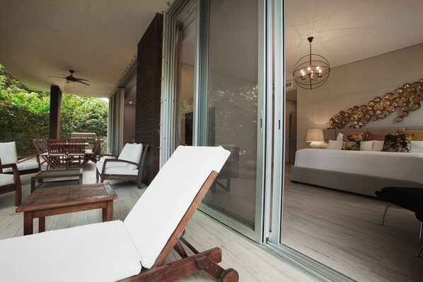 A modern living room with a sofa, a coffee table, and a chair. There is a sliding glass door leading to a balcony.
