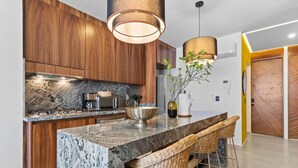 A modern kitchen with wooden cabinets, a marble countertop, and a central island with bar stools.