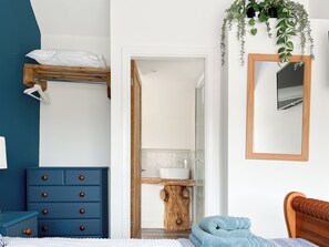 A bedroom with a blue dresser, a wooden headboard, a mirror, and a plant. - 3 bedroom accommodation in Ashover, near Matlock. (Ashover, near Matlock.)