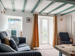 A cozy living room with a sofa, a chair, a table, and a window with curtains. - 3 bedroom accommodation in Ashover, near Matlock. (Ashover, near Matlock.)