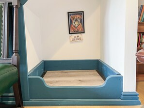 Ett rum med en blå hundsäng, en inramad bild av en bulldog och en skylt med texten ”Hundens hus”.