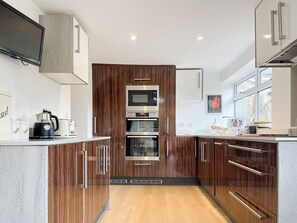 A modern kitchen with wooden cabinets, stainless steel appliances, and a large window providing natural light. - 3 bedroom accommodation in Ashover, near Matlock. (Ashover, near Matlock.)