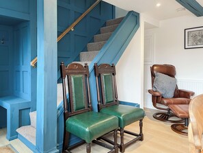 A staircase with blue walls and wooden railings, a green upholstered bench, and a brown leather armchair with a cushion. - 3 bedroom accommodation in Ashover, near Matlock. (Ashover, near Matlock.)