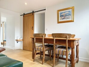 A dining area with wooden chairs and a table, a sliding barn door, and a framed painting on the wall. - 3 bedroom accommodation in Ashover, near Matlock. (Ashover, near Matlock.)