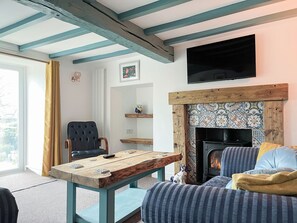 A cozy living room with a fireplace, a wooden table, a sofa, and a dog. - 3 bedroom accommodation in Ashover, near Matlock. (Ashover, near Matlock.)
