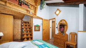Une pièce en bois avec un lit, une commode, un miroir et une petite étagère en bois ornée de fleurs.