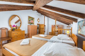 Habitación de hotel con muebles de madera, cama, escritorio, silla, espejo y un cuadro en la pared.