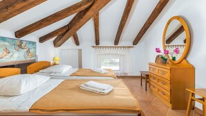 A bedroom with two beds, wooden beams, a large mirror, a dresser, and a painting on the wall.