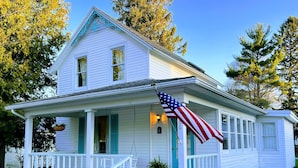 Een wit huis met een veranda en een Amerikaanse vlag.