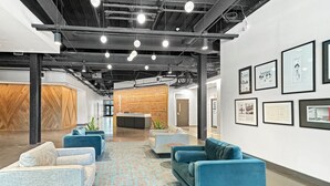 A modern office space with a reception area, blue sofas, a patterned carpet, and framed pictures on the walls. - Rare Luxury: Apartment with Unparalleled Elegance (Rochester)
