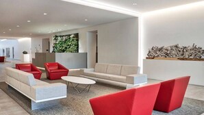 A modern living room with a sofa, red chairs, a coffee table, and a decorative wall. - Tower280 LUXE One-Bedroom Corner Unit with Views! (Rochester)