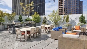 An outdoor patio with a dining table, chairs, a grill, and wicker furniture. - Tower280 LUXE One-Bedroom Corner Unit with Views! (Rochester)
