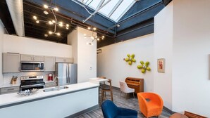 A modern kitchen with a central island, stainless steel appliances, and a skylight above.
