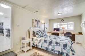 A bedroom with a bed, desk, chair, and a view of the kitchen. - Charming Orem Home w/ Yard - Near BYU & UVU! (Orem)