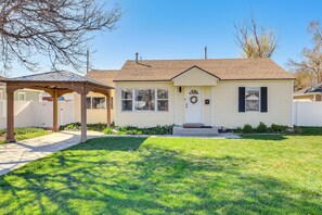 A single-story house with a front porch, a small garden, and a clear sky. - Charming Orem Home w/ Yard - Near BYU & UVU! (Orem)