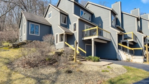 A modern multi-story building with a gray exterior, multiple balconies, and a central staircase. - Galena Townhome w/ Deck & Golf Course View! (Galena)