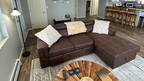 A modern living room with a brown sectional sofa, a round coffee table, and a patterned rug. - Beautiful Mountainside Escape (Anchorage)