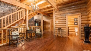 A log cabin interior with a wooden staircase, a chandelier, and rustic furniture. - Legend Crest Lodge (Sevierville)