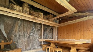 A rustic wooden room with a long table and benches, a stone wall, and a wooden ceiling with beams. - House with garden in the middle of the terraced vineyards of the Cembra Valley (giovo)