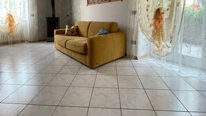 A spacious living room with a sofa, a fireplace, and large windows with sheer curtains. - House with garden in the middle of the terraced vineyards of the Cembra Valley (giovo)