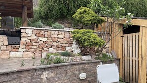 A stone wall with a statue, a wooden fence, and a white lounge chair. - House with garden in the middle of the terraced vineyards of the Cembra Valley (giovo)