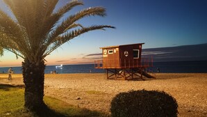 Une tour de surveillance sur une plage, avec un palmier et un buisson à proximité.
